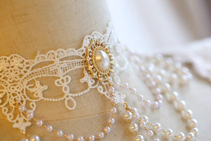 Pearl necklace with a decorative clasp on a lace garment