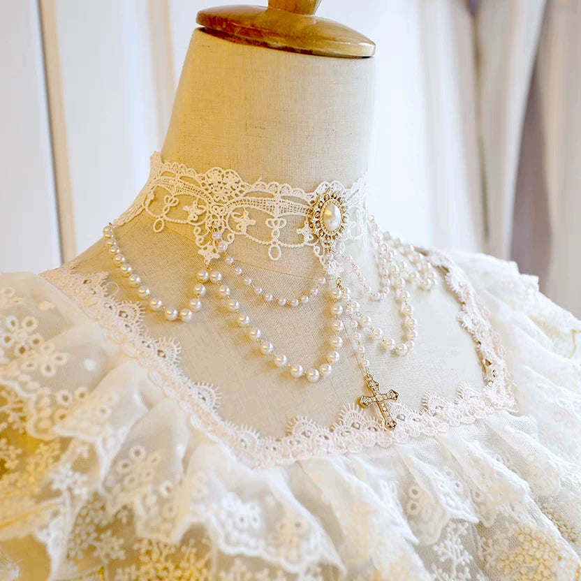 Mannequin wearing a white lace dress with a pearl necklace.