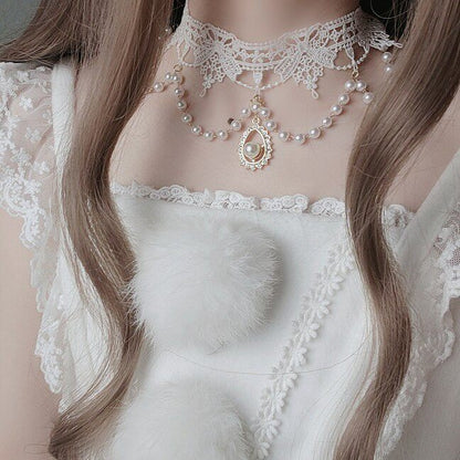 Close-up of a person wearing a delicate pearl necklace and lace garment.