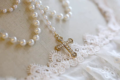 Pearl necklace with a cross pendant on a lace fabric background