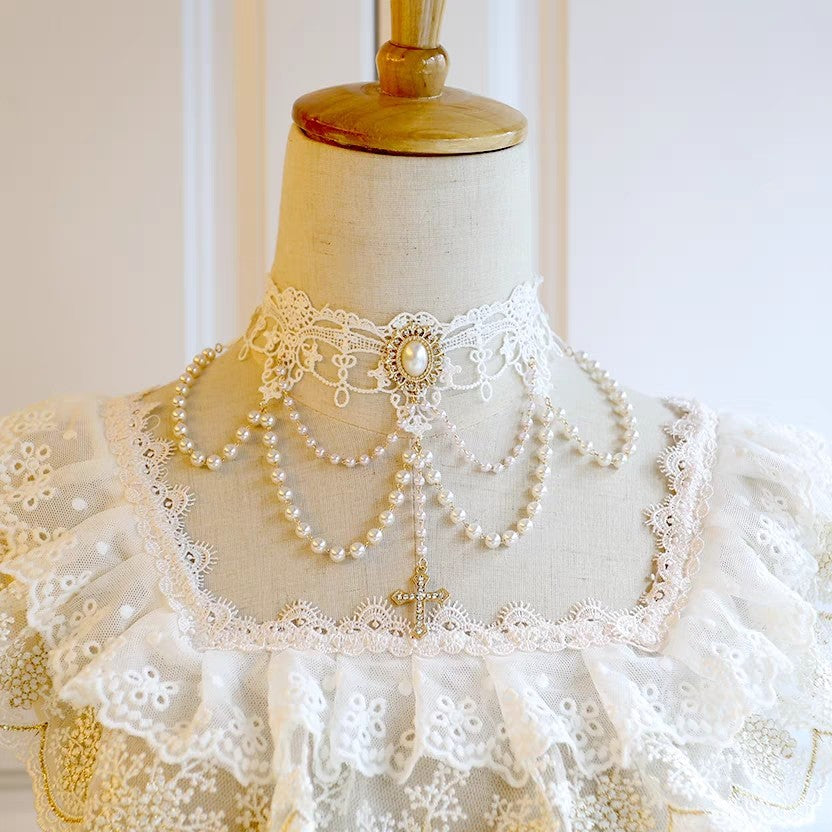 Mannequin wearing a white lace dress with a pearl necklace on a plain background