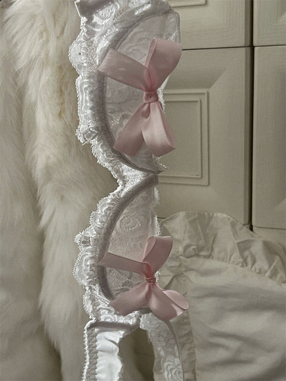 Decorative headboard with lace details and pink bows against a neutral wall.