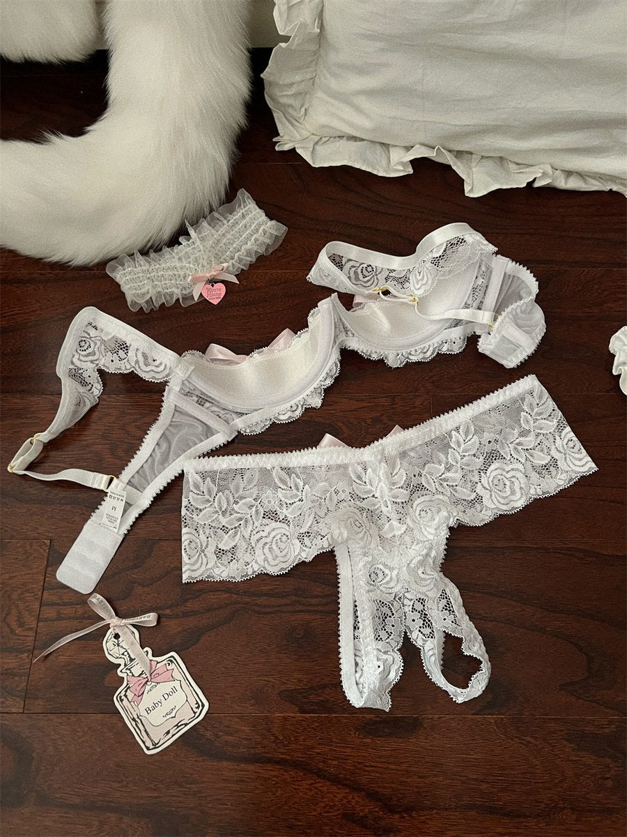 Set of white lace lingerie on a wooden surface with a fluffy white rug in the background.