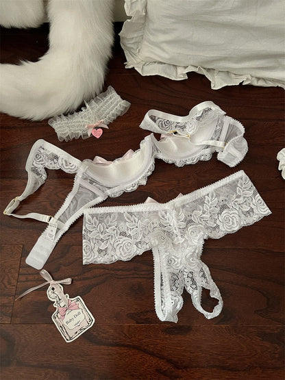 Set of white lace lingerie on a wooden surface with a fluffy white rug in the background.