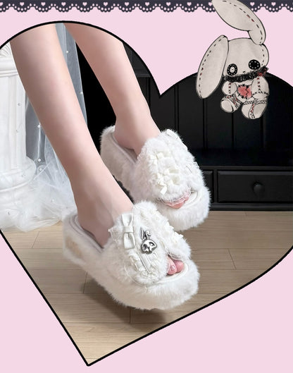 White fluffy open-toe slippers with bow and heart embellishments, shown on a person's feet in a styled indoor setting with a pink heart-shaped frame and bunny illustration.
