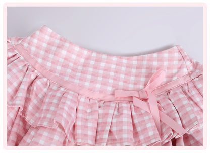 Pink and white gingham check skirt with a ruffled waistband and a matching pink ribbon bow at the center, shown against a light gray background.