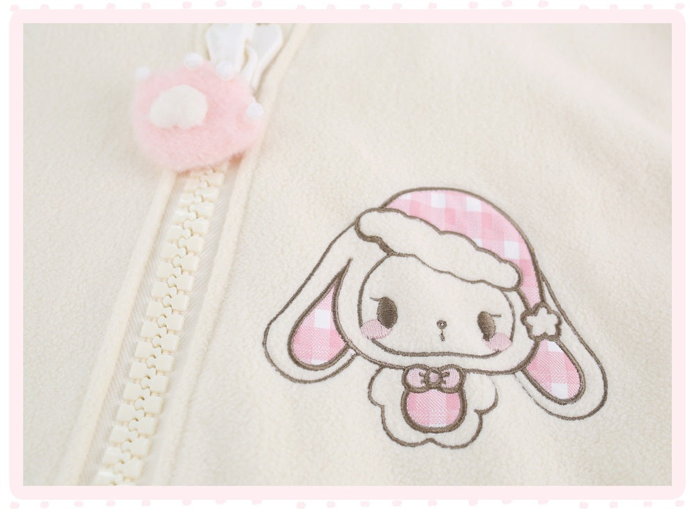 Close-up of a cream-colored zippered garment featuring an embroidered cartoon bunny character with pink gingham accents and a matching pink plush zipper pull.