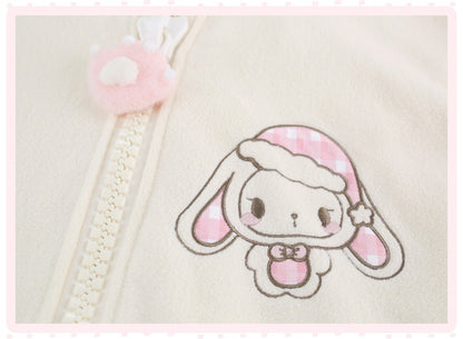 Close-up of a cream-colored zippered garment featuring an embroidered cartoon bunny character with pink gingham accents and a matching pink plush zipper pull.