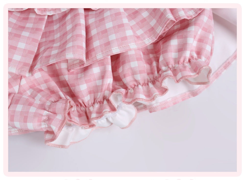 Pink and white gingham check ruffled skirt detail with layered ruffles and a white inner lining, shown on a light background.