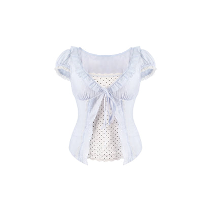 A light blue ruffled short-sleeve blouse with a tie at the neckline, layered over a white polka-dot top, shown against a plain white background.