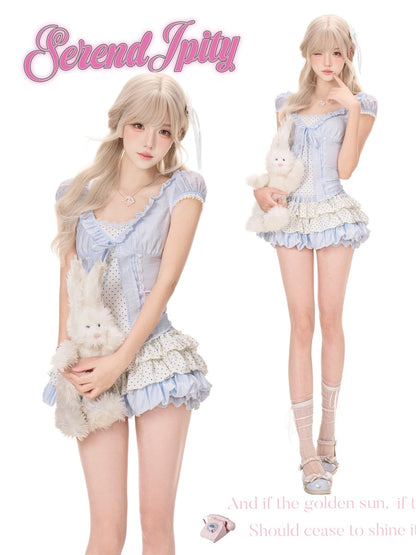 A fashion catalog-style composite showing a young woman modeling a pastel blue and white frilly dress in two poses against a white background. The left figure holds a white plush bunny, and the right figure stands barefoot in lace-up shoes while holding the same bunny.