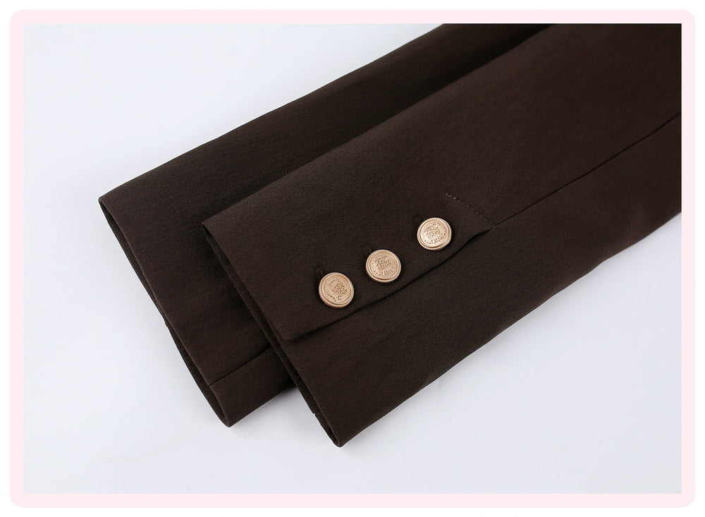 A close-up of a dark brown suit jacket sleeve folded over, showing three gold buttons on the cuff, set against a clean white background with a light pink border.