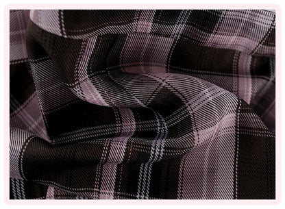 A close-up of draped plaid fabric with a black base and intersecting light pink and white stripes, framed by a thin pink border.