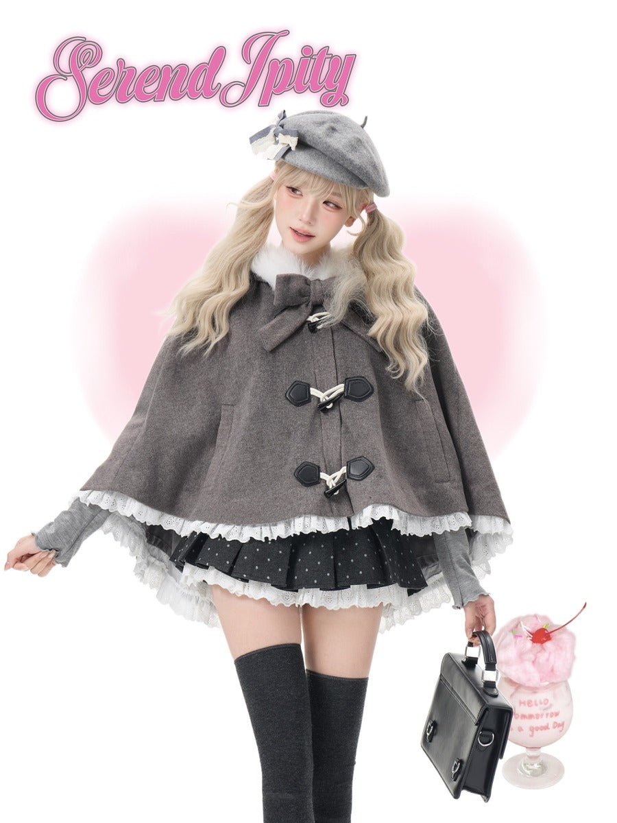 A model wearing a grey wool-like cape with toggle closures, a black polka-dot pleated skirt with white ruffles, a grey beret, and black knee-high socks, holding a black handbag. The brand name 'Serendipity' is written in pink at the top left, with a pink heart-shaped glow behind the model.