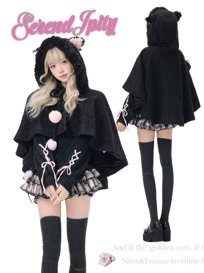 A model wearing a black hooded cape with bear ears, pink pom-poms, and pink lace-up details, shown from both front and back views on a white background with 'Serendipity' branding.