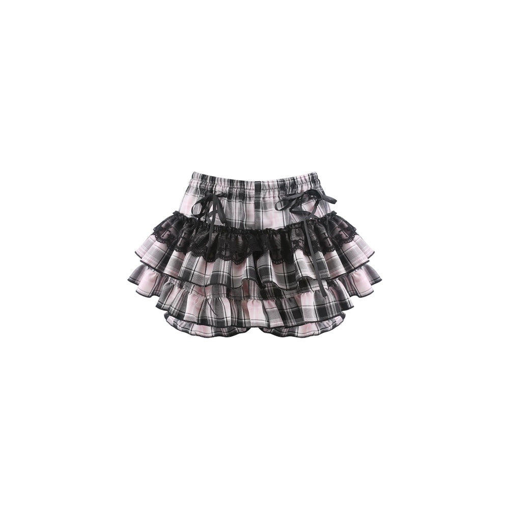 A tiered ruffle skirt in a black, white, and pink plaid pattern with sheer black mesh layers and matching black ribbon ties at the waist, shown against a plain white background.