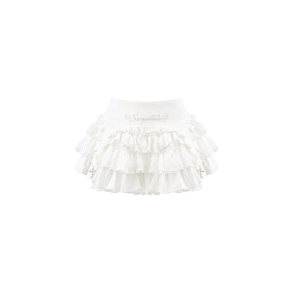 A white ruffled skirt with multiple tiers of delicate fabric and small embroidered details, shown against a plain white background.