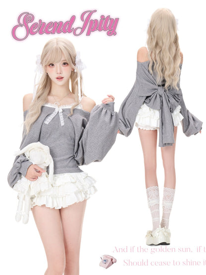 A model shown in two views wearing a gray off-the-shoulder long-sleeve top with a bow detail, white ruffled shorts, and white lace socks.
