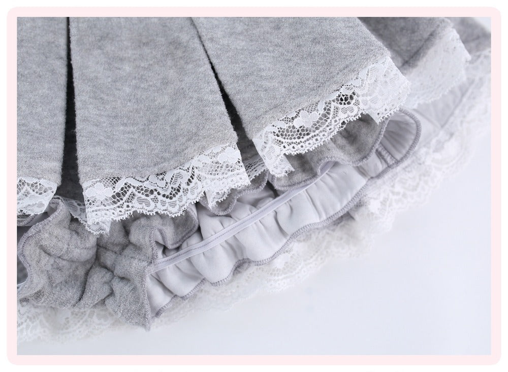 Close-up of a light gray pleated skirt with white lace trim and ruffled layers, shown on a white background.