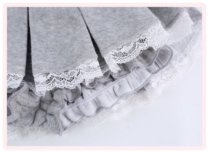 Close-up of a light gray pleated skirt with white lace trim and ruffled layers, shown on a white background.
