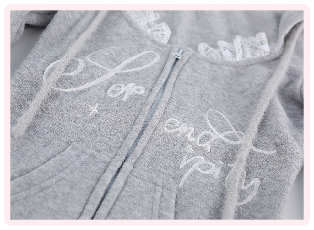 A close-up of a light gray zip-up hoodie with white embroidered script text on the front, lace trim along the neckline, and drawstrings, shown against a pale background.