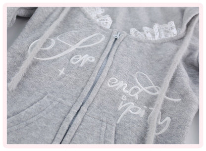 A close-up of a light gray zip-up hoodie with white embroidered script text on the front, lace trim along the neckline, and drawstrings, shown against a pale background.