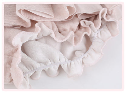 Close-up of a light pink ruffled fabric, showing the soft texture and layered edges.