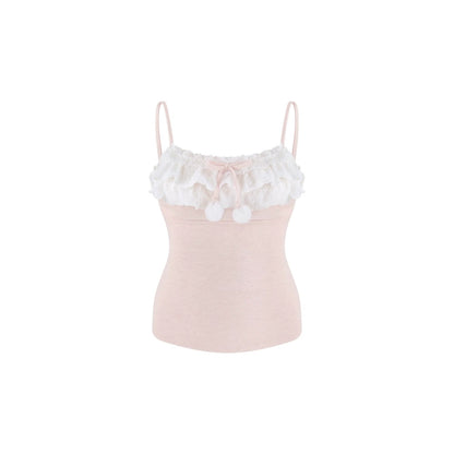 A light pink camisole top with a white ruffled lace collar, a small pink bow, and two white pom-poms, shown against a plain white background.