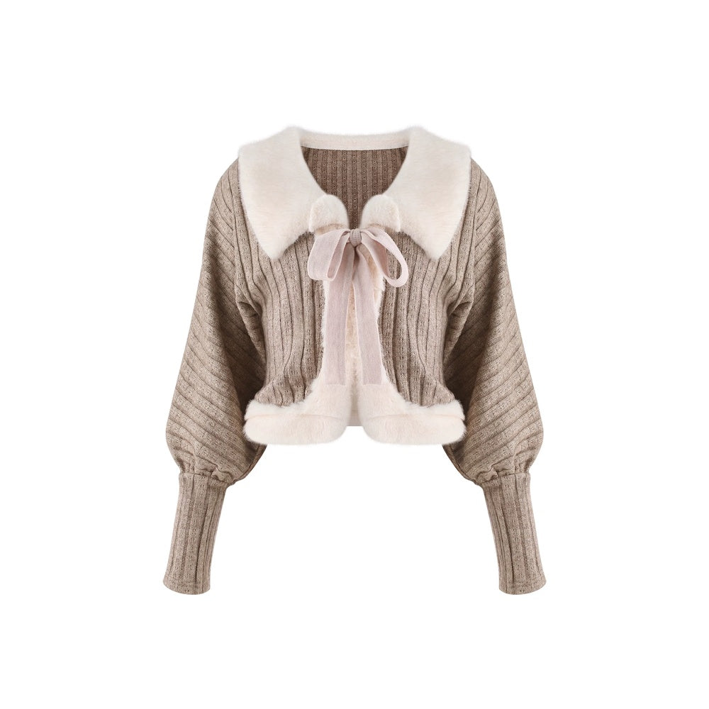 A cropped ribbed knit cardigan sweater in taupe with a large cream faux-fur collar, a matching cream bow tie at the neck, and cream faux-fur trim along the collar and hem, shown on a plain white background.