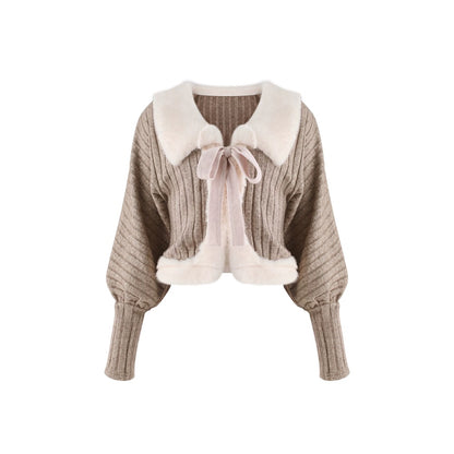 A cropped ribbed knit cardigan sweater in taupe with a large cream faux-fur collar, a matching cream bow tie at the neck, and cream faux-fur trim along the collar and hem, shown on a plain white background.