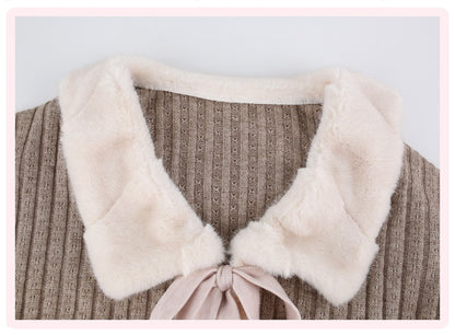 Close-up of a ribbed knit top with a large cream faux-fur collar and a pale pink ribbon tie at the neckline.