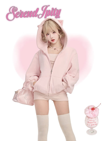 Person wearing a pink hoodie with cat ears, standing next to a dessert with pink cream.
