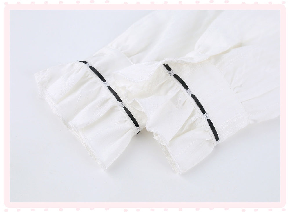 White ruffled fabric detail with black decorative accents, shown on a light background with a pink dotted border.