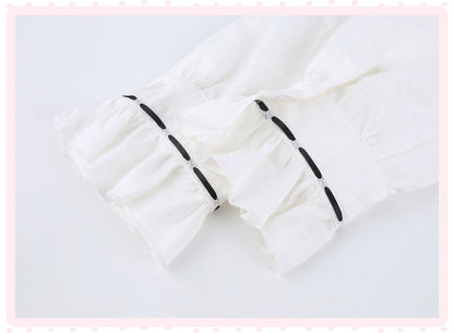 White ruffled fabric detail with black decorative accents, shown on a light background with a pink dotted border.