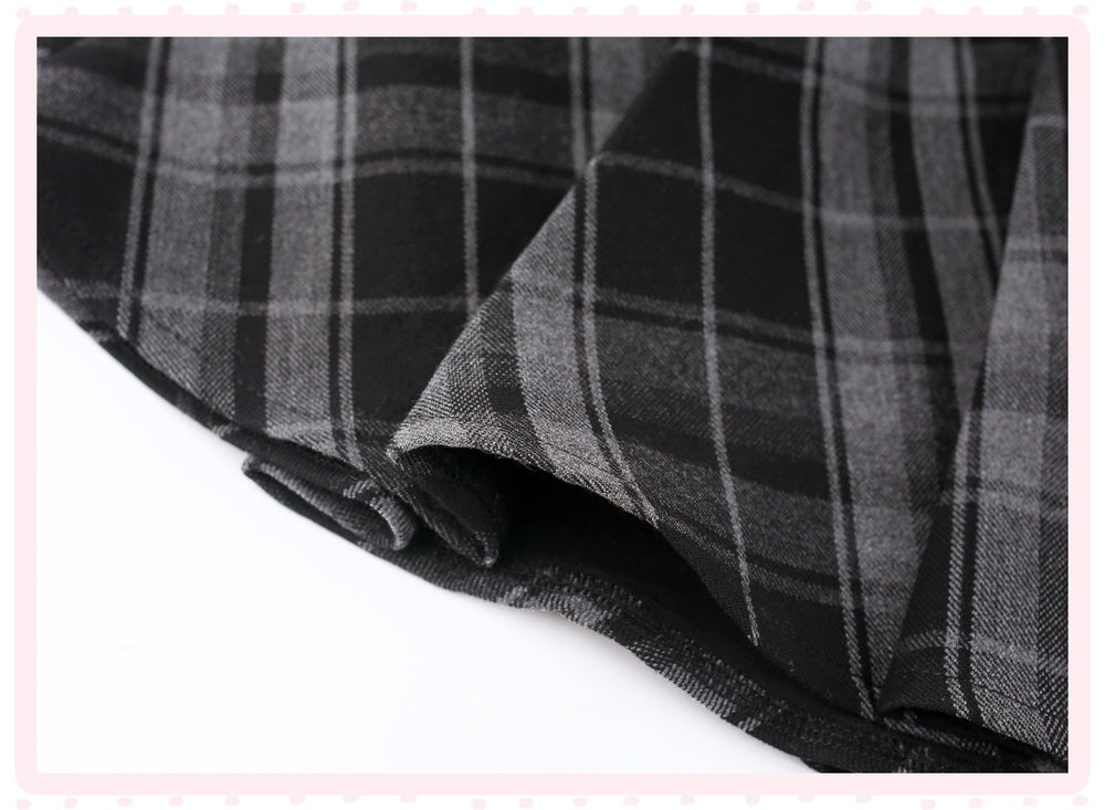 A close-up of a folded black and gray plaid fabric, showing its woven texture and pattern details against a white background with a light pink border.