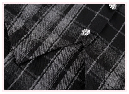 Close-up of a black and gray plaid shirt fabric with decorative silver floral buttons, framed by a light pink border.