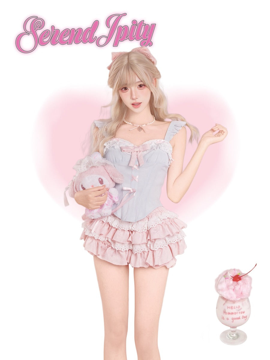 A young woman with long blonde hair models a pastel pink and light blue Lolita-style outfit, holding a plush toy.