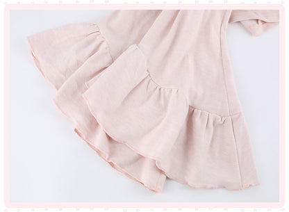 A close-up of a light pink tiered ruffle dress or skirt made from lightweight fabric, shown against a white background with a decorative pink border.