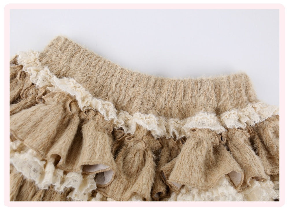 Close-up of a beige textured skirt with layered ruffles and cream lace trim, shown against a plain light background.