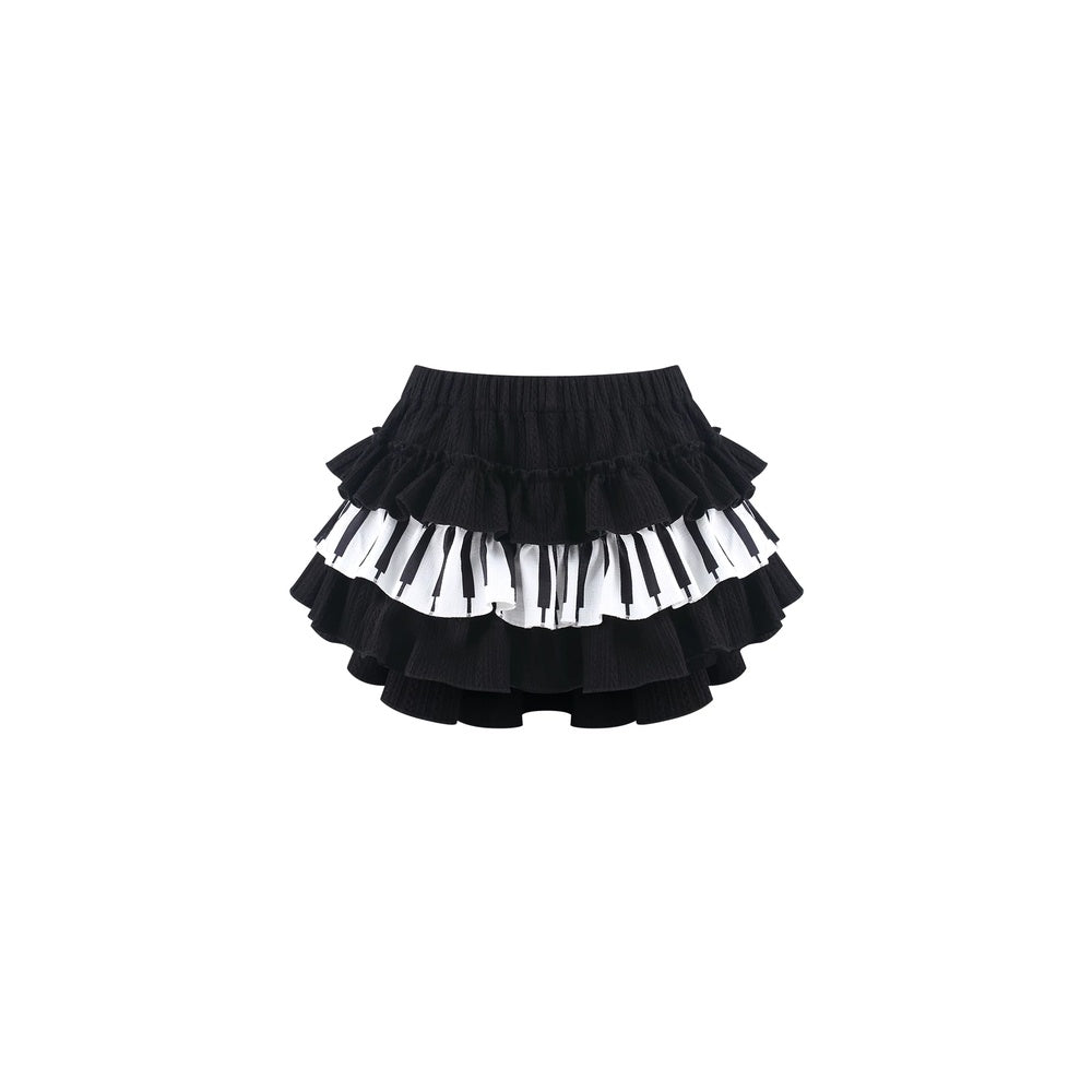 A black ruffled skirt with alternating horizontal bands of white and black piano keys, shown against a plain white background.