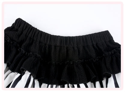 Black pleated ruffled skirt with a textured knit waistband, shown laid flat against a white background with a pink border.