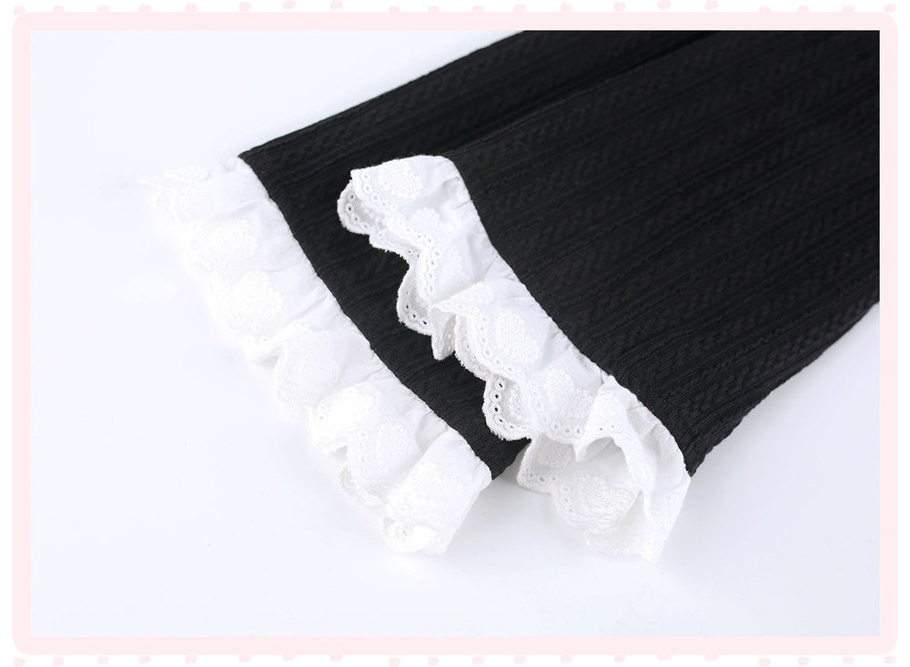 Black textured knit fabric with white lace ruffle trim, shown folded on a white background.