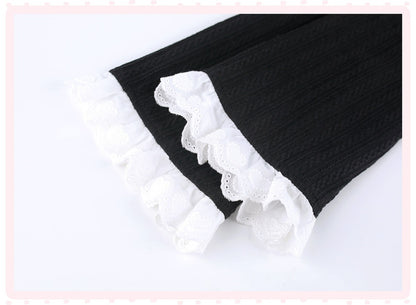 Black textured knit fabric with white lace ruffle trim, shown folded on a white background.