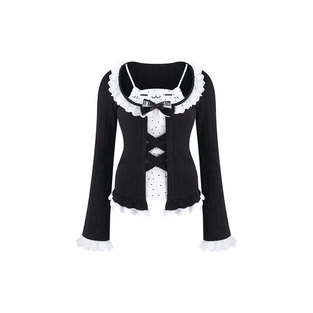 A black long-sleeve ribbed top with white ruffled trim, a white polka-dot front panel, and a black bow at the neckline, shown on a plain white background.