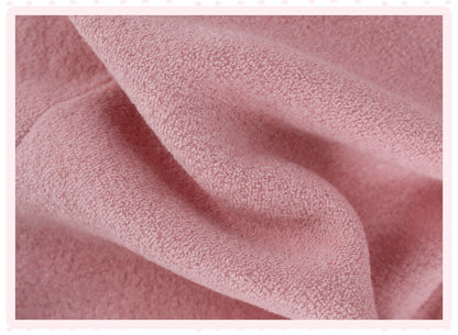 A close-up of soft pink textured fabric with gentle folds and a fine terry-like surface, framed by a pale pink border.