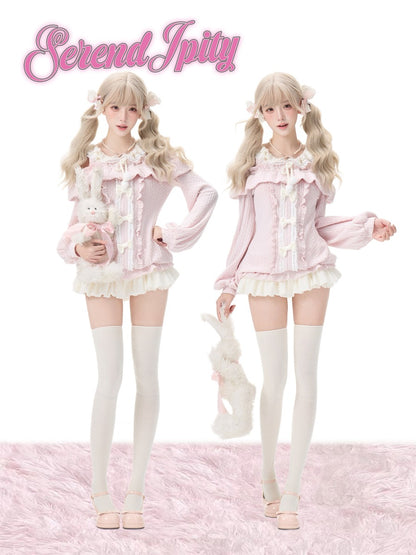 Two models wearing matching pastel pink and white frilly Lolita-style outfits with bunny accessories, standing against a white background with a pink fluffy rug. The name 'Serendipity' is displayed in pink script at the top.