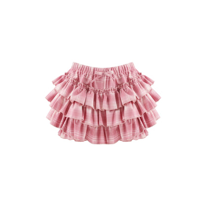 A pink tiered ruffle skirt with a subtle plaid pattern, featuring an elastic waistband and a small bow detail at the center front, shown against a plain white background.