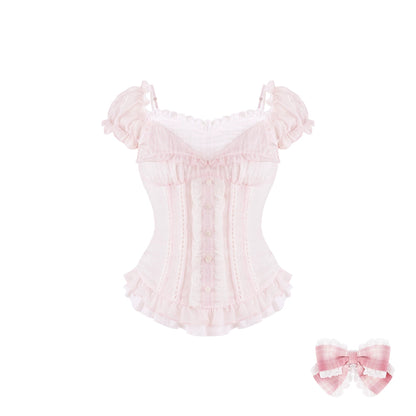A light pink ruffled lace corset top with puff sleeves and a sweetheart neckline, shown on a plain white background with a matching pink gingham bow accessory in the lower right corner.