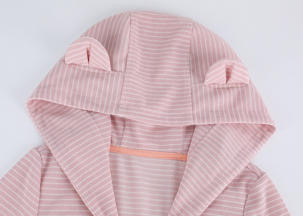 A close-up of a hooded garment in light pink fabric with thin white vertical stripes and small ear details on the hood, shown against a plain light background.