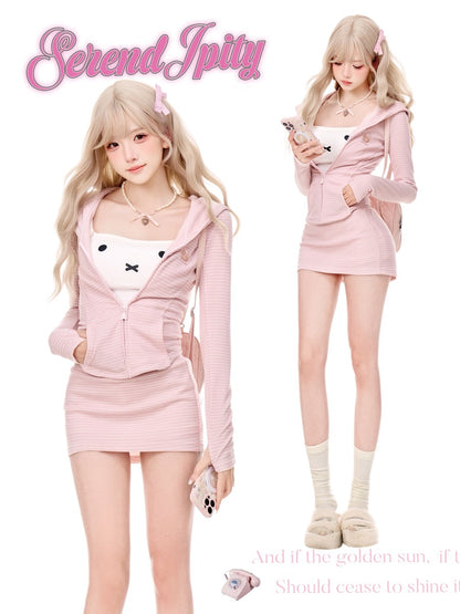 A model wearing a pink ribbed zip-up hoodie and matching mini skirt set with a white cartoon face insert, shown in two poses on a white background